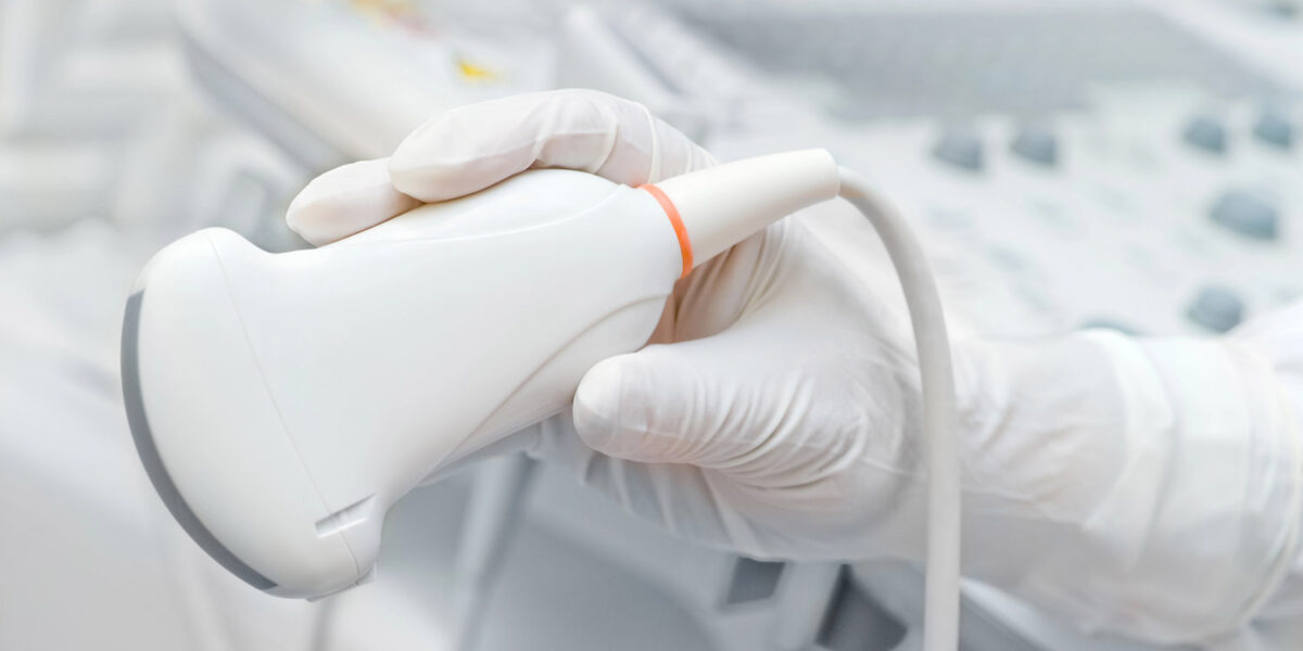 Eine Hand hält einen Ultraschallkopf.
