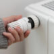 Frau dreht an Heizungsthermostat