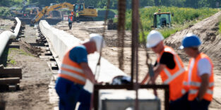 Mitarbeiter der Ontras Gastransport GmbH arbeiten bei der Erneuerung der Ferngasleitung Lauchhammer-Strehla an einem Rohrstrang zur Gewässerquerung, auch Düker genannt, am Ufer der Elbe. Die Erneuerung des rund 35 Kilometer lange Abschnitts soll eine effiziente Energieversorgung für die Regionen zwischen Lauchhammer und Riesa sicherstellen. (Luftaufnahme mit Drohne)