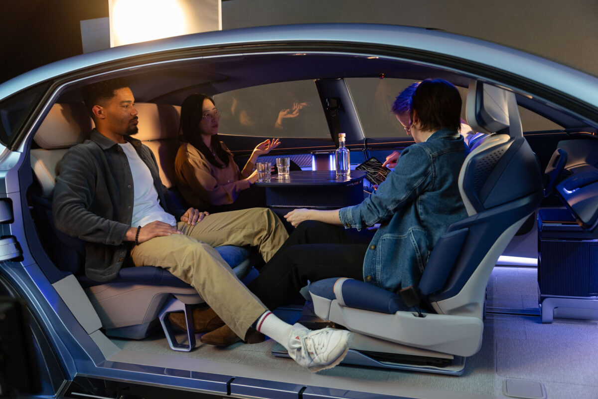 Blick in das Innere des Forvia Saphir, in dem vier Menschen um einen Tisch herum sitzen.