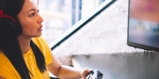 Eine junge Frau sitzt vor dem Fernseher und spielt Videospiele inklusive Kopfhörer und Controller