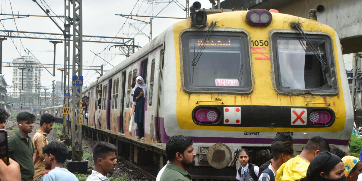 Menschenmenge an einem gelben Nahverkehrszug in Mumbai, Indien