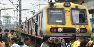 Menschenmenge an einem gelben Nahverkehrszug in Mumbai, Indien