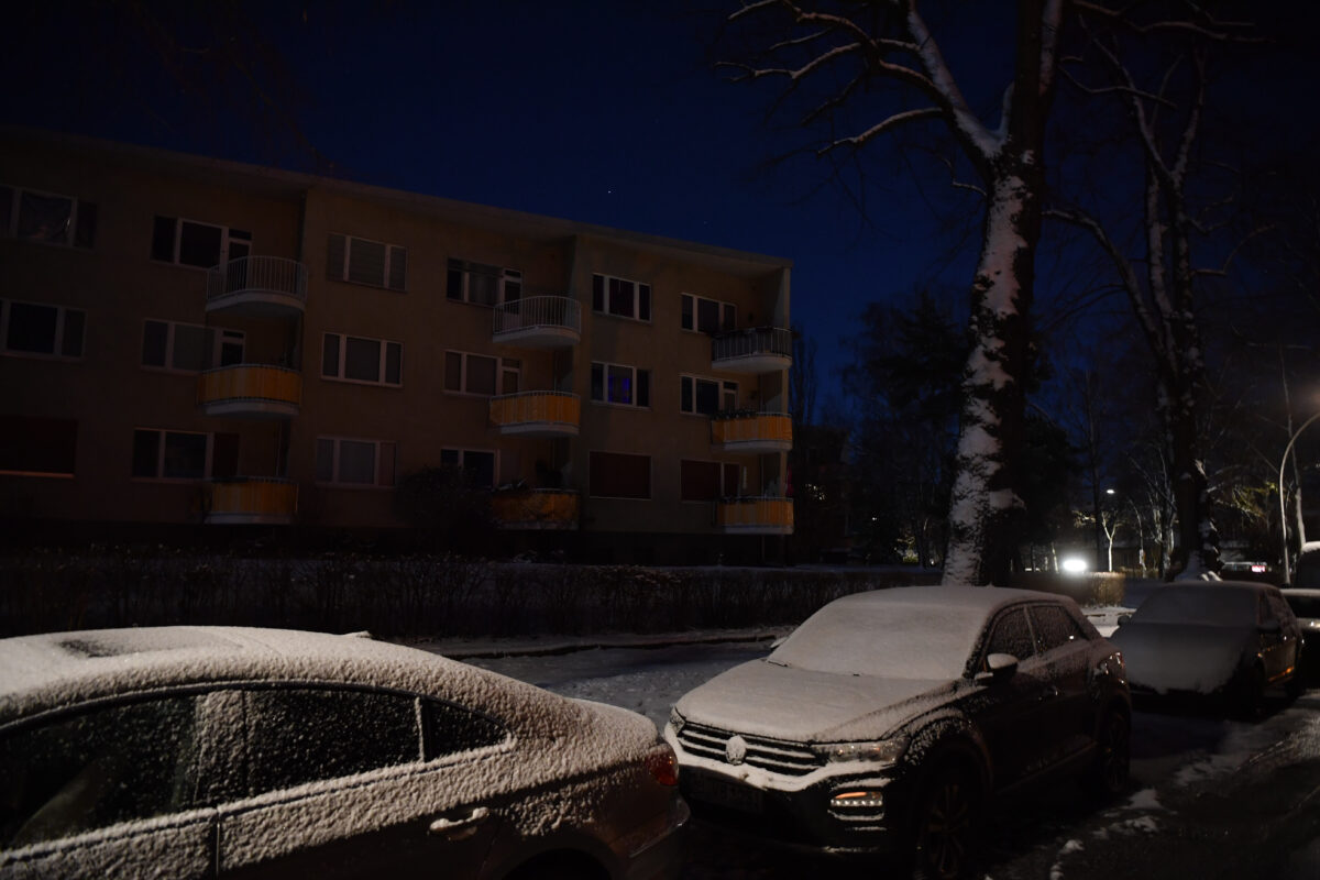 Verschneite Autos vor Mehrfamilienhaus in Berlin.
