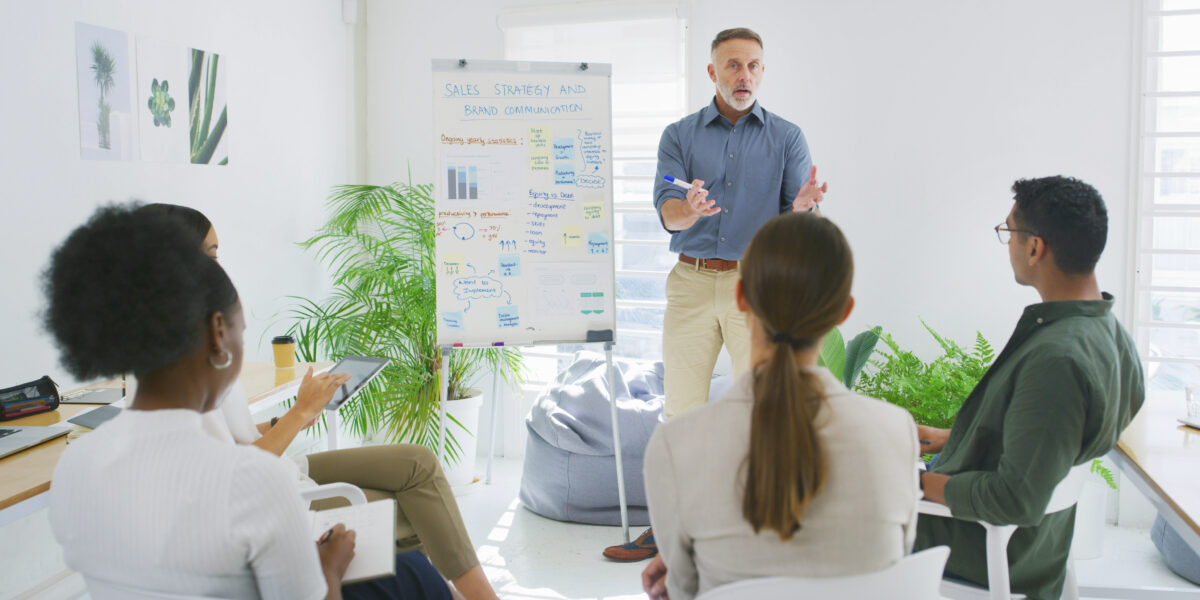 Weiterbildung. Ein Mann steht und erklärt etwas.