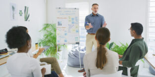 Weiterbildung. Ein Mann steht und erklärt etwas.