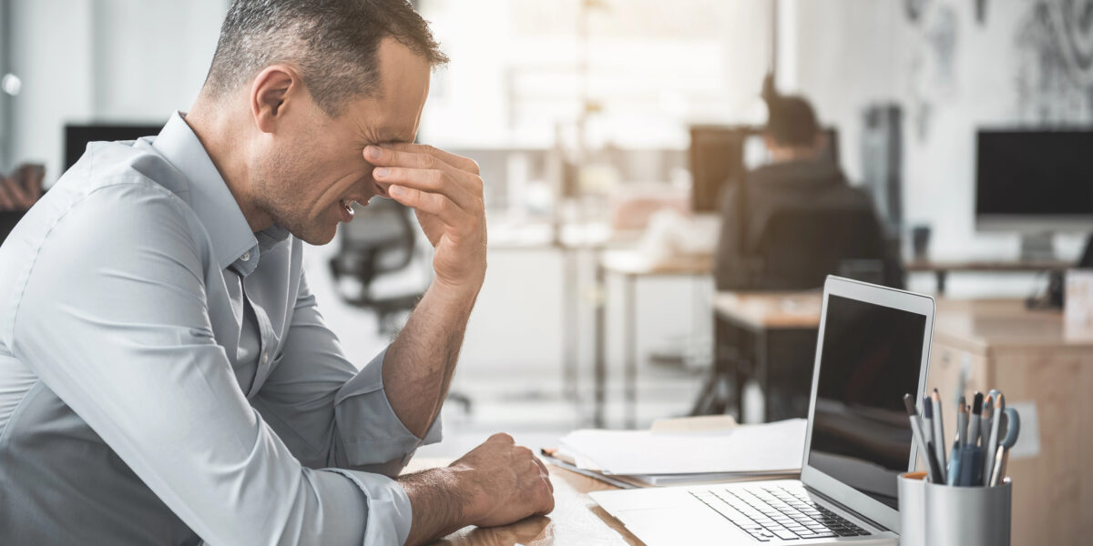 Ein Mann sitzt krank im Büro.