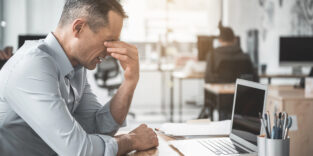 Ein Mann sitzt krank im Büro.