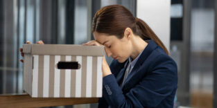 junge Frau mit Karton, der Kopf traurig gesenkt