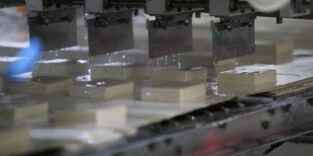 Industrielle Tofu-Herstellung: Metallpressen drücken Sojamilch unter Zugabe von Salzlake zu Tofu-Blöcken.