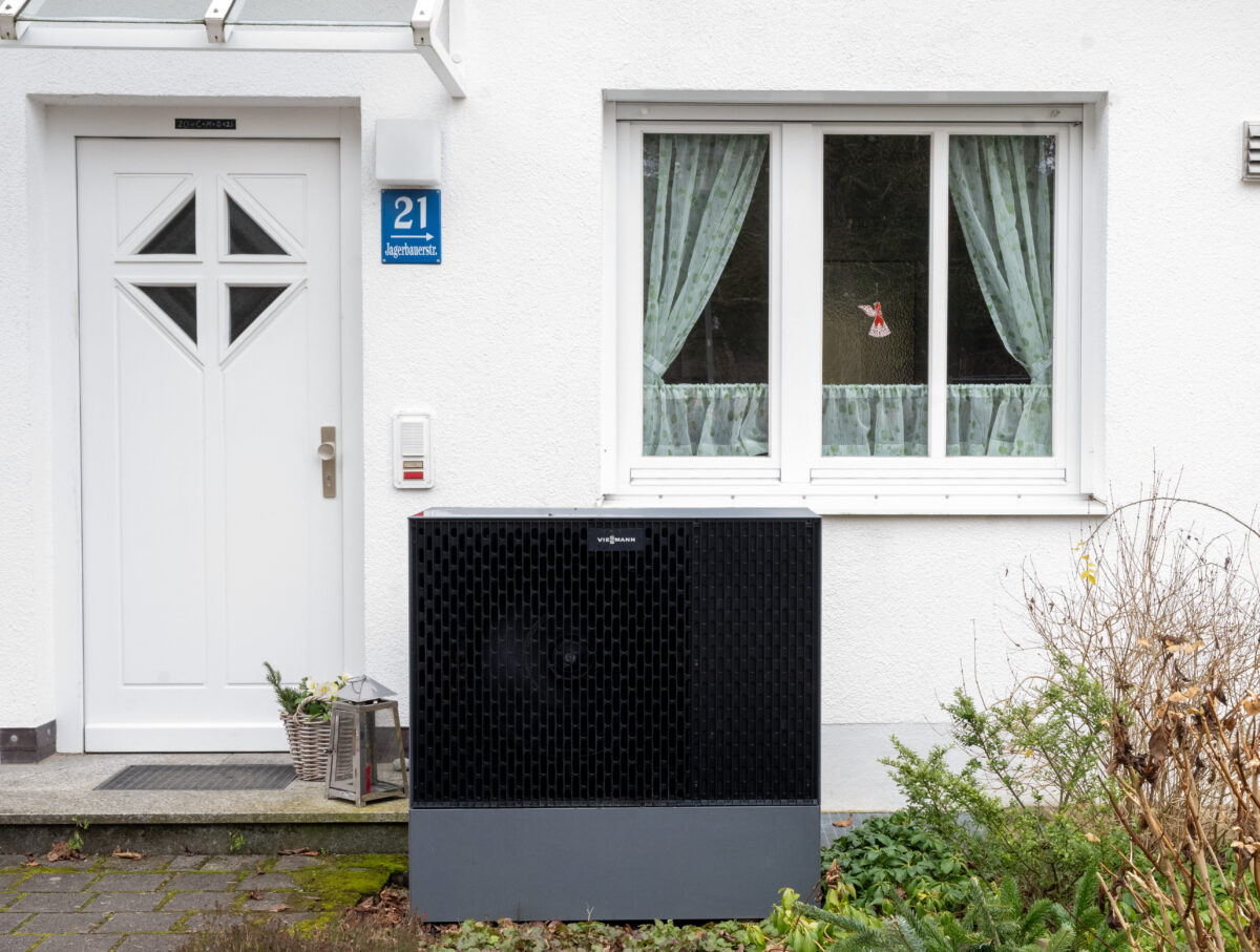 Eine Luft-Wasser-Wärmepumpe vor einem Einfamilienhaus. 