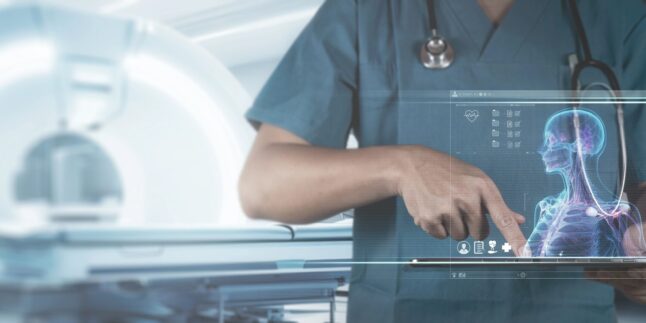 Ein Mediziner tippt auf einem laptop im Hintergrund ein MRT