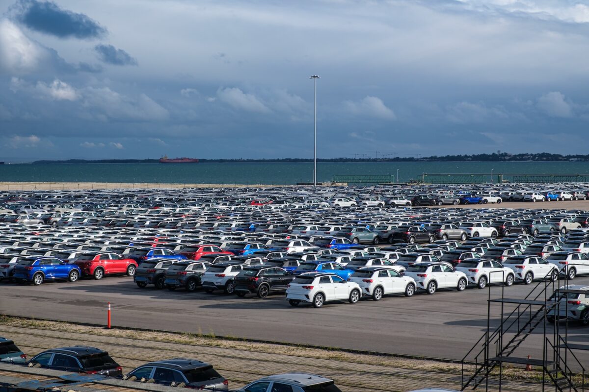 Blick auf zahlreiche Fahrzeuge, die in der Nähe eines Hafens stehen und auf ihre Verschiffung warten.