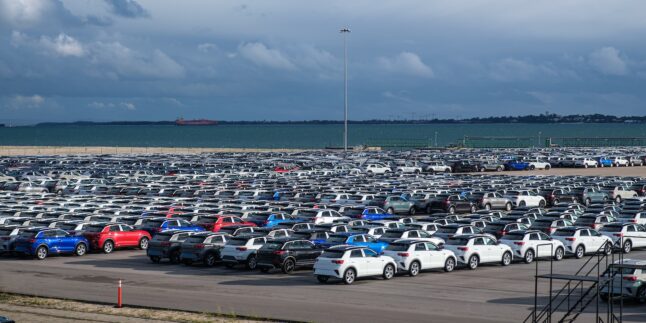 Blick auf zahlreiche Fahrzeuge, die in der Nähe eines Hafens stehen und auf ihre Verschiffung warten.