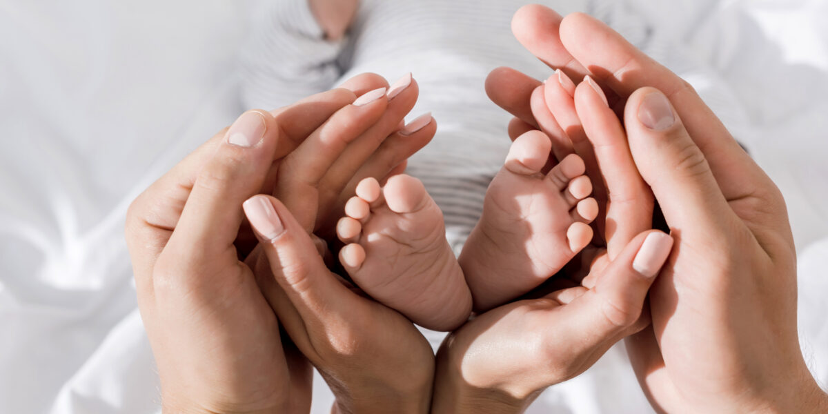 Hände umschließen Baby-Füße