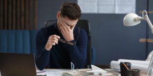 Ein Mann sitzt übermüdet am Schreibtisch