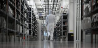 Eine Mitarbeiterin läuft durch den Reinraum einer Halbleiterfertigung von Nexperia