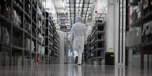 Eine Mitarbeiterin läuft durch den Reinraum einer Halbleiterfertigung von Nexperia