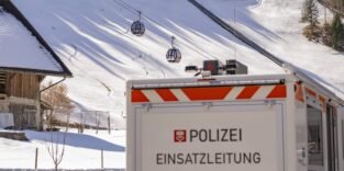 Ein Polizei Einsatzfahrzeug steht bei der Talstation der Titlisbahnen mit zwei Gondeln der Gondelbahn Engelberg-Titlis Express, nach dem auf Truebsee eine Gondel der selben Bahn abstuerzte