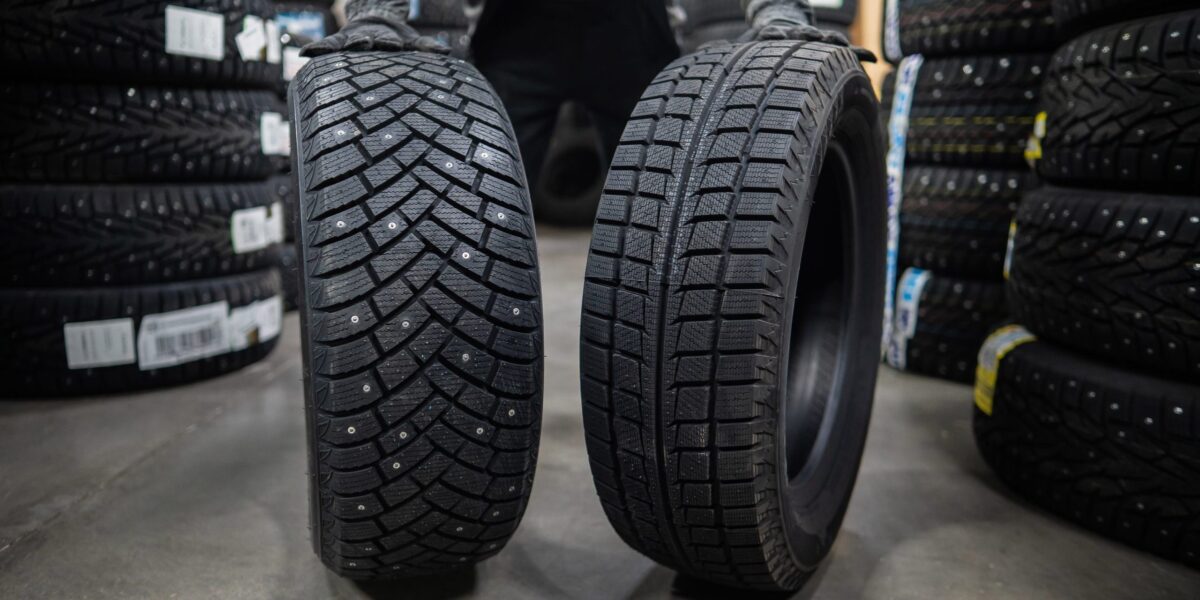 Mechaniker lagert neue Sommer- und Winterreifen in der Werkstatt. Vergleich von Rädern für verschiedene Jahreszeiten.