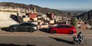 Die Audi RS 5 Limousine in Bedfordgrün und der Audi RS 5 Avant in Progressivrot auf einer offenen Landstraße vor der Bergkulisse des Atlasgebirges.