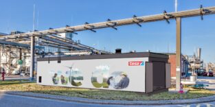 Außenansicht des tesa-Werks in Hamburg-Hausbruch mit dem Schriftzug „we do" und Industrierohren über dem Werksgelände