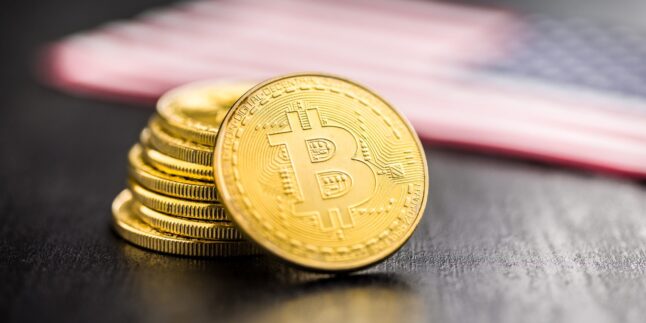 Bitcoin Goldmünze. Kryptowährung mit amerikanischer Flagge auf schwarzem Tisch.