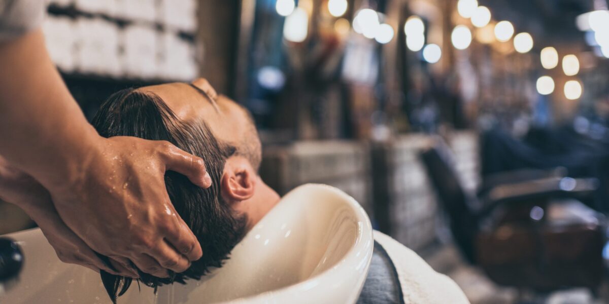 Friseur wäscht Mann die Haare