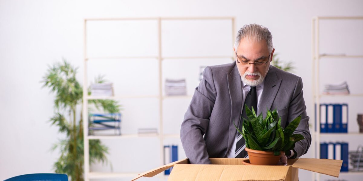 Ein älterer Herr packt seine Sachen im Büro ein.