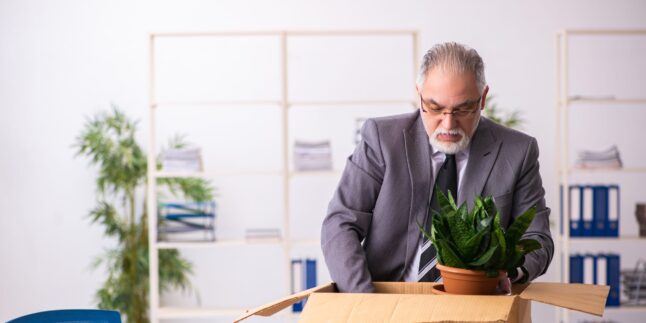 Ein älterer Herr packt seine Sachen im Büro ein.
