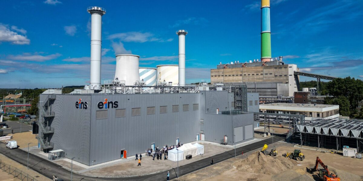 Luftaufnahme von zwei großen Kraftwerksgebäuden - ein neues im Vordergrund mit Aufschrift "eins", ein altes direkt dahinter mit buntem Schornstein.