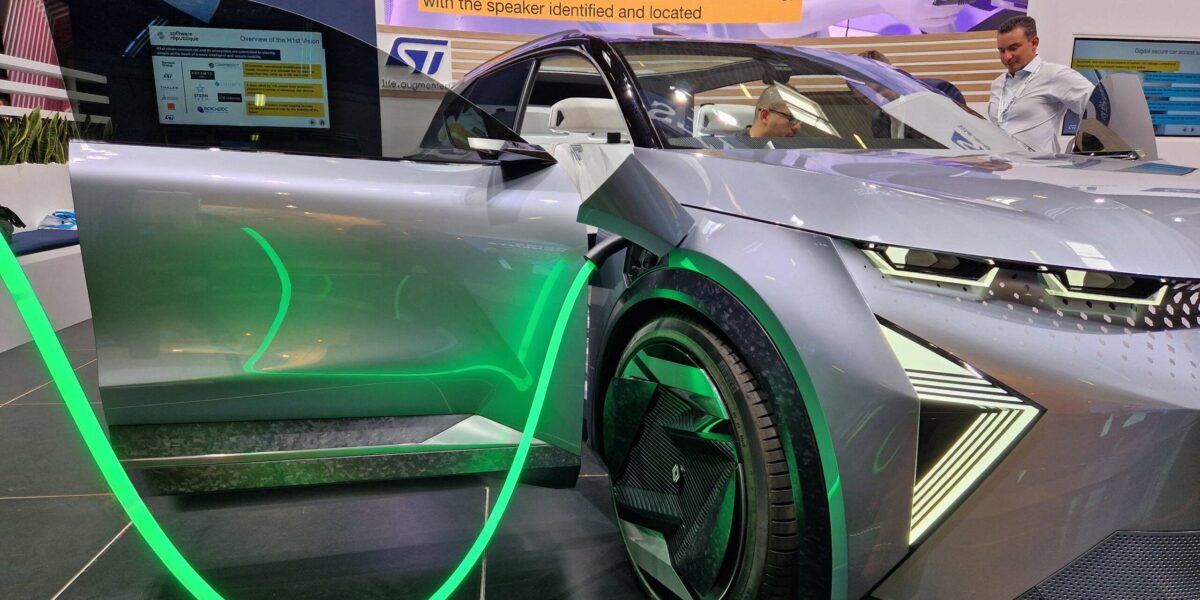 Futuristisches silbernes Elektro-Konzeptfahrzeug mit grüner LED-Beleuchtung auf einem Messestand.