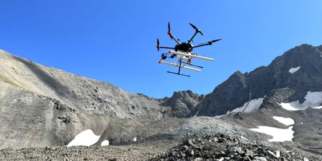 Vor dem blauen Himmel hebt eine Drohne, die ein Bodenradargerät an Bord hat, vom Galena Creek Rock Glacier in Wyoming ab