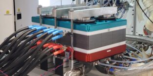 Ein großformatiger PEM-Brennstoffzellen-Stack mit blauen Anschlüssen und Kabeln auf einem Teststand im Brennstoffzellentestzentrum HyFaB des ZSW in Ulm.