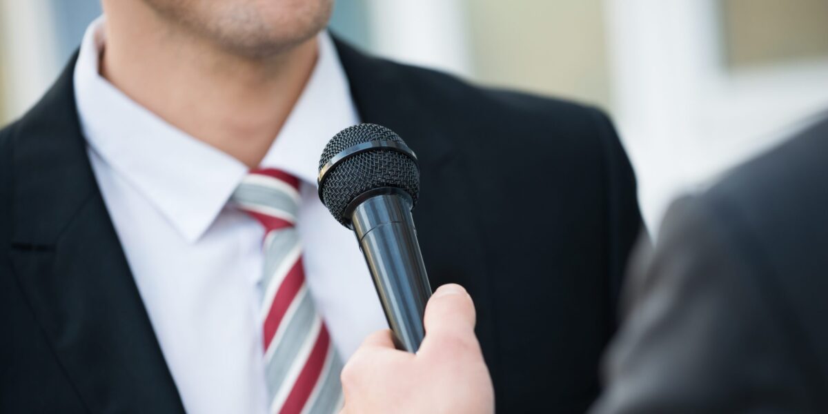 Mann mit Schlips vor Mikro