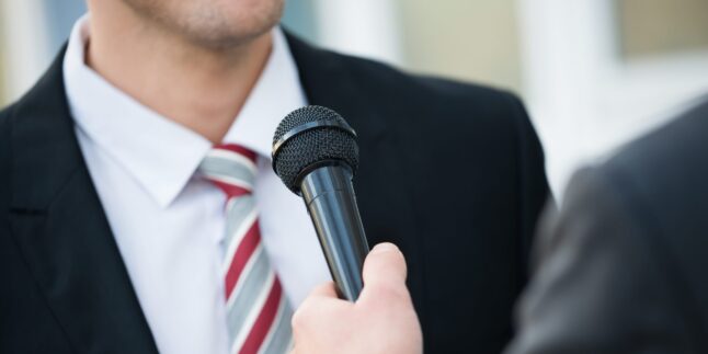 Mann mit Schlips vor Mikro