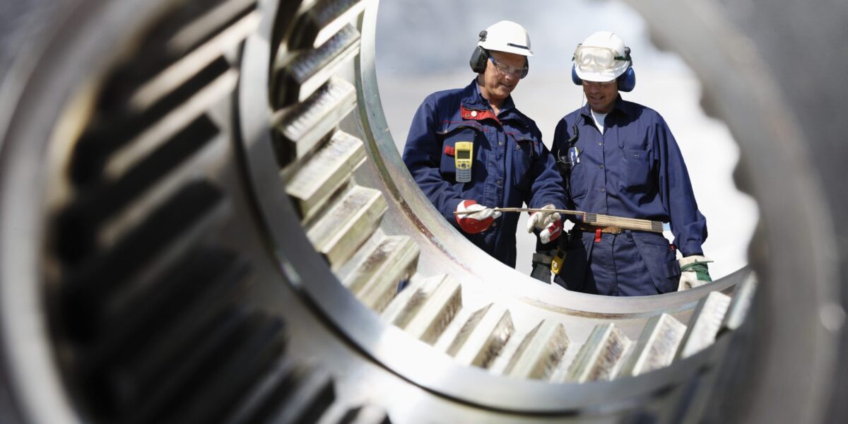 industriearbeiter durch eine große zahnradachse gesehen