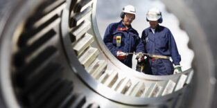 industriearbeiter durch eine große zahnradachse gesehen