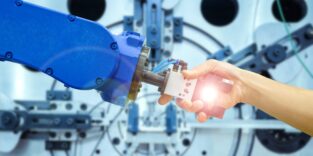 Ein Mensch fasst den Greifer eines Roboters an, wie beim Händedruck