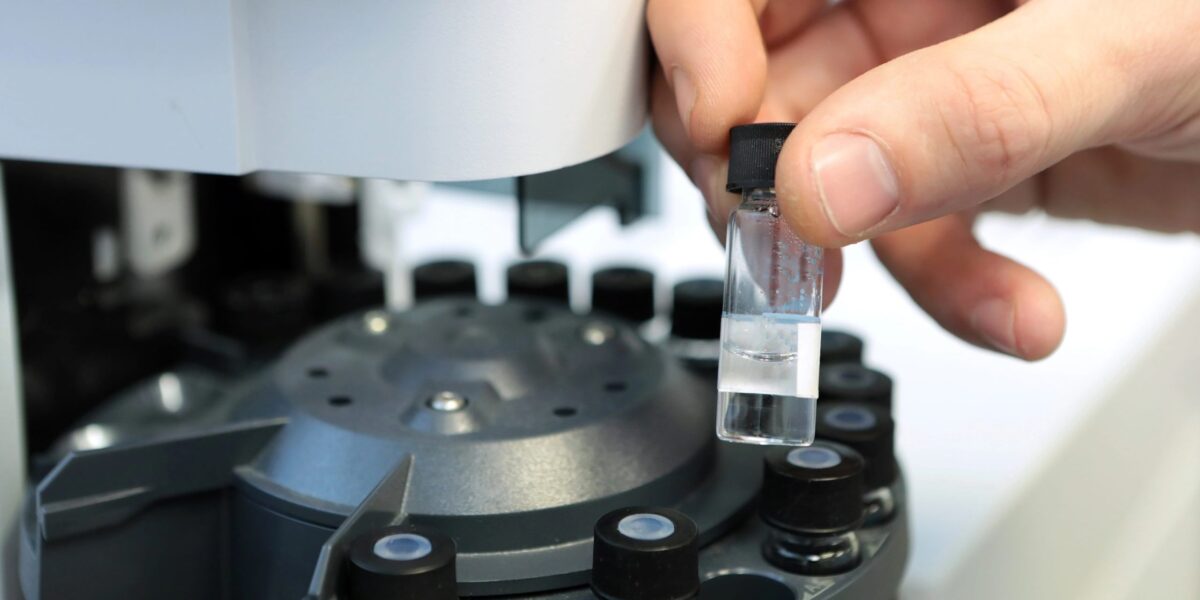 Ein Forscher hält ein Reagenzglas zur Analyse im Gas-Flüssigkeits-Chromatographen