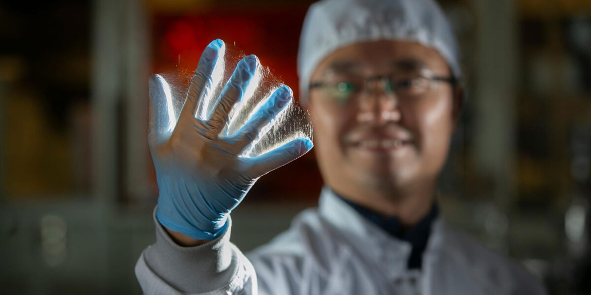 Daewoo Han, Assistenzprofessor an der Universität von Cincinnati, hält eine mit einem Handschuh bekleidete Hand hoch, die mit elektrogesponnenen Nanofasern bedeckt ist. Foto: Joseph Fuqua II