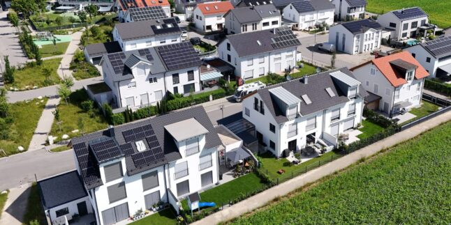 Luftaufnahme Siedlung mit Doppelhaushälften. Einige mit, eine ohne Solaranlagen auf dem Dach.