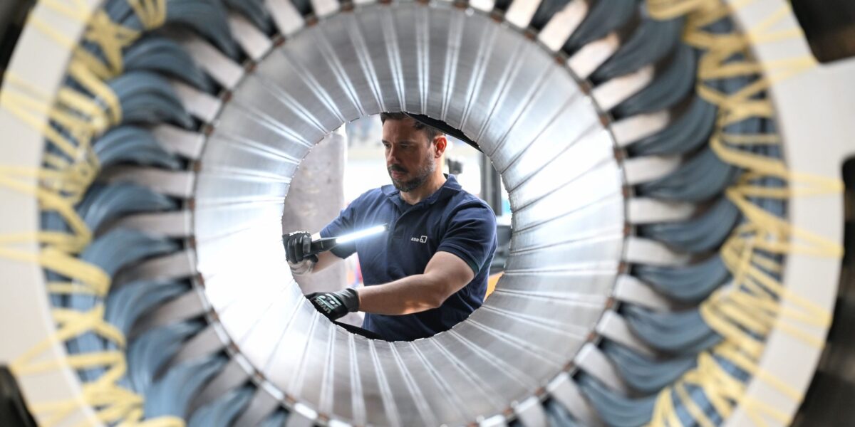 Ein Mitarbeiter arbeitet in einer Werkshalle an einem großen runden Bauteil