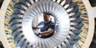 Ein Mitarbeiter arbeitet in einer Werkshalle an einem großen runden Bauteil