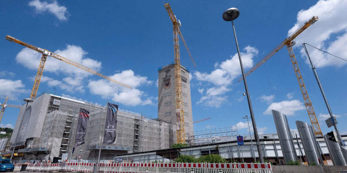 Der eingerüsteten Stuttgarter Hauptbahnhof ist neben Baukränen und Laternen zu sehen sind.