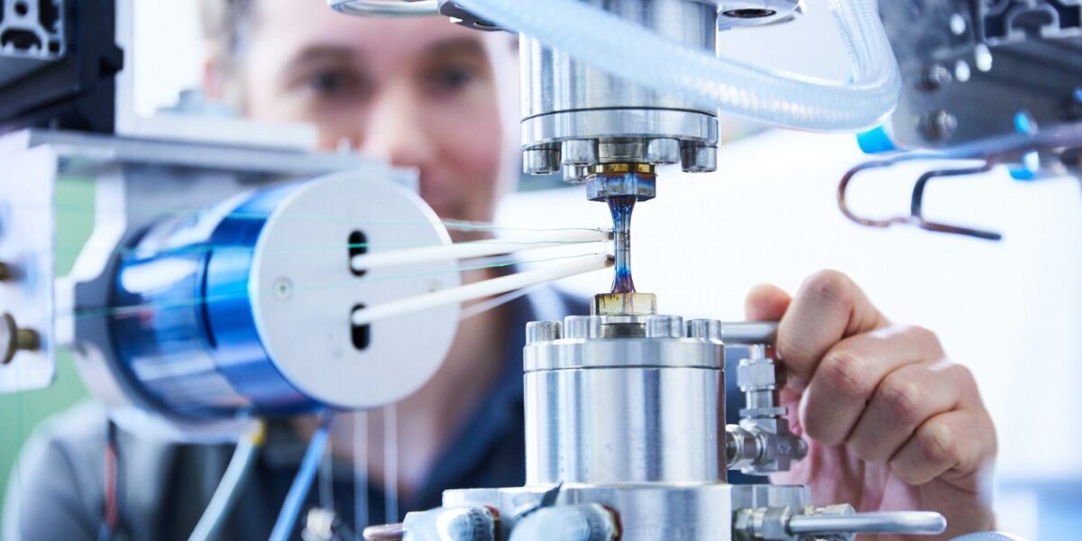 Forscher untersucht eine eingespannte Werkstoffprobe in einer Prüfmaschine am Fraunhofer IWM
