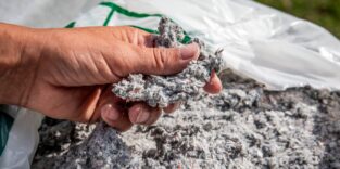 Mann greift in Sack mit Zelluloseflocken
