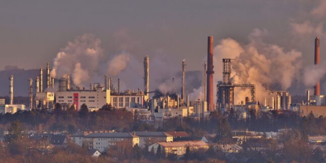Dampfende Chemieanlagen Sonnenaufgang, im Vordergrund Wohnbebauung. Burghausen in Oberbayern.