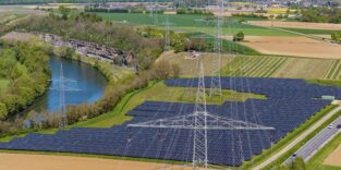 Luftaufnahme Stromtrasse vor Solarpark in Flußaue