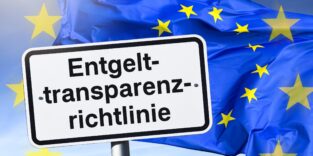 Schild mit Aufschrift Entgelttransparenzrichtlinie vor EU-Fahne, Fotomontage +++ nur redaktionelle Nutzung Foto: picture alliance / CHROMORANGE | Christian Ohde